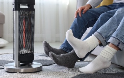 Photo of Couple near electric heater on floor at home, closeup