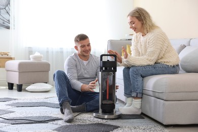 Photo of Happy couple near electric heater at home