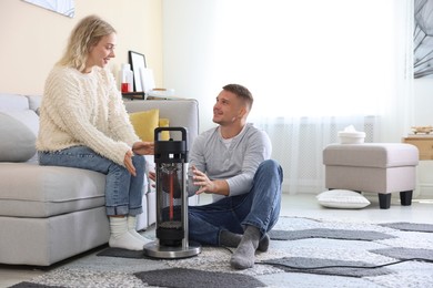 Photo of Happy couple near electric heater at home