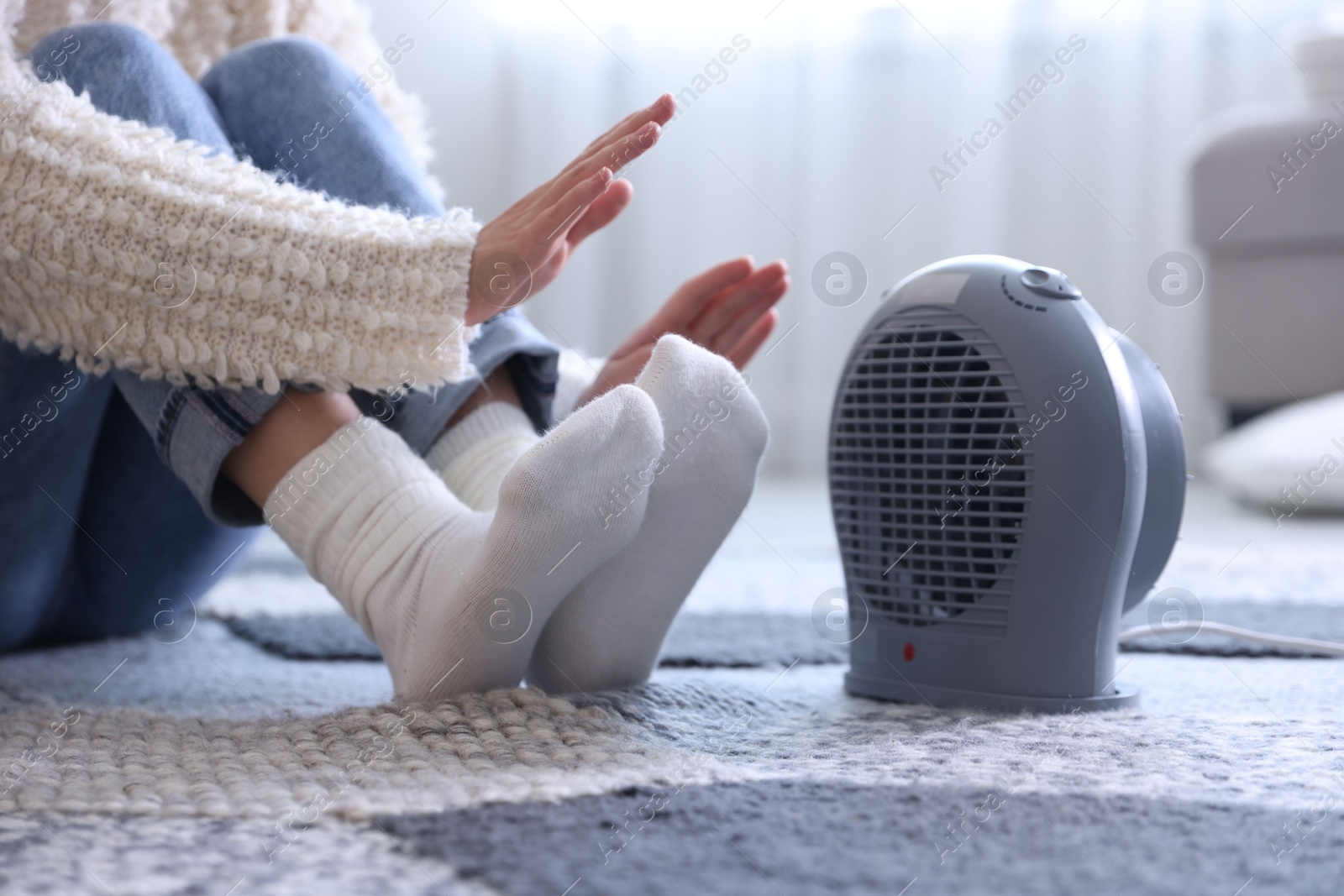 Photo of Young woman near electric heater at home, closeup