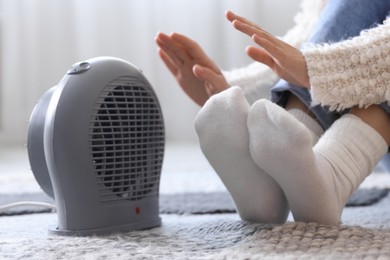 Photo of Young woman near electric heater at home, closeup