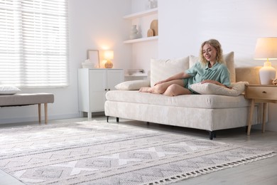 Photo of Happy young woman resting on sofa at home, space for text