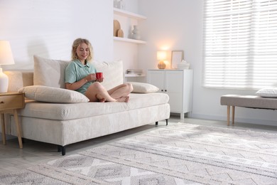 Photo of Happy young woman resting on sofa at home, space for text