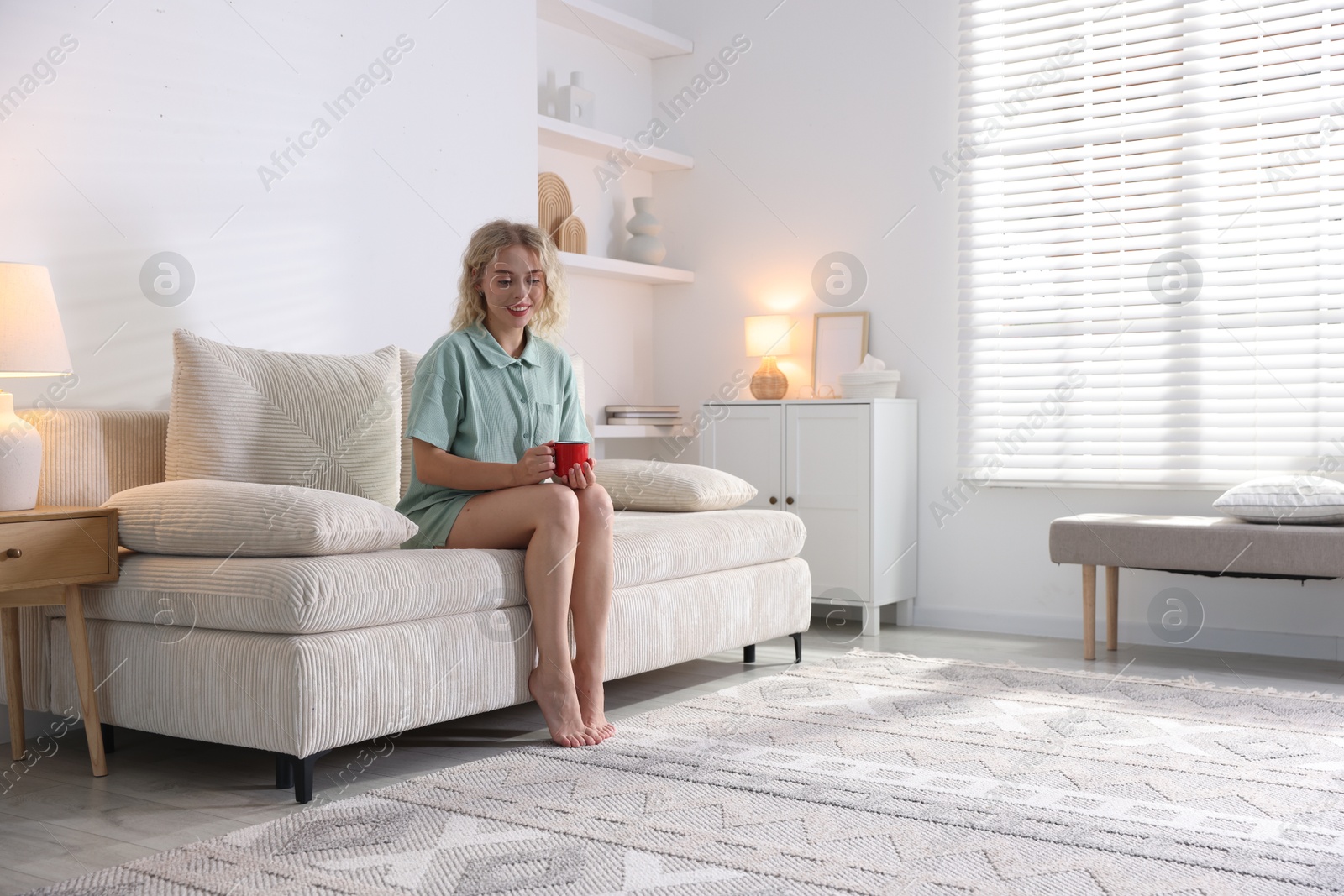 Photo of Happy young woman resting on sofa at home, space for text