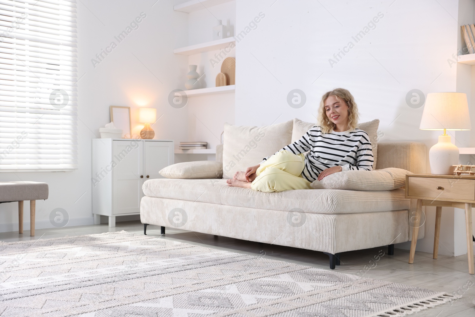 Photo of Happy young woman resting on sofa at home, space for text