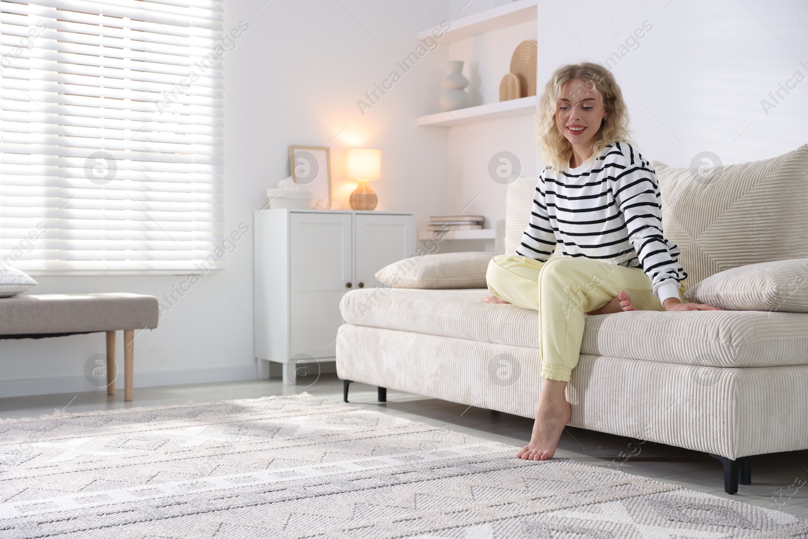 Photo of Happy young woman resting on sofa at home, space for text
