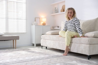 Photo of Happy young woman resting on sofa at home, space for text