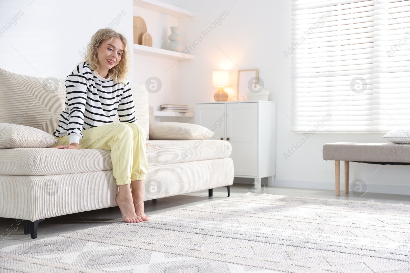 Photo of Happy young woman resting on sofa at home, space for text