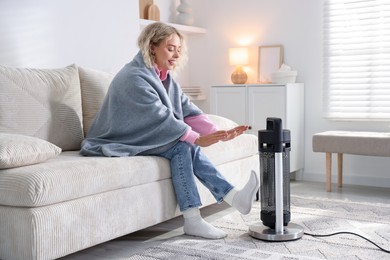 Photo of Young woman near electric heater at home