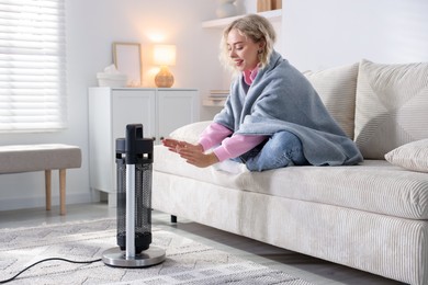 Photo of Young woman near electric heater at home