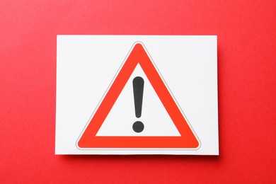 Photo of Risk. Sheet of paper with warning sign on red background, top view