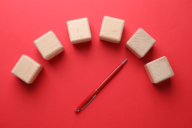 Photo of Blank wooden cubes and pen on red background, flat lay with space for text