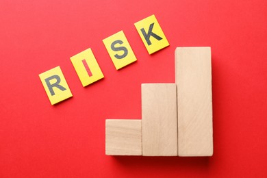 Photo of Word Risk and wooden blocks on red background, flat lay