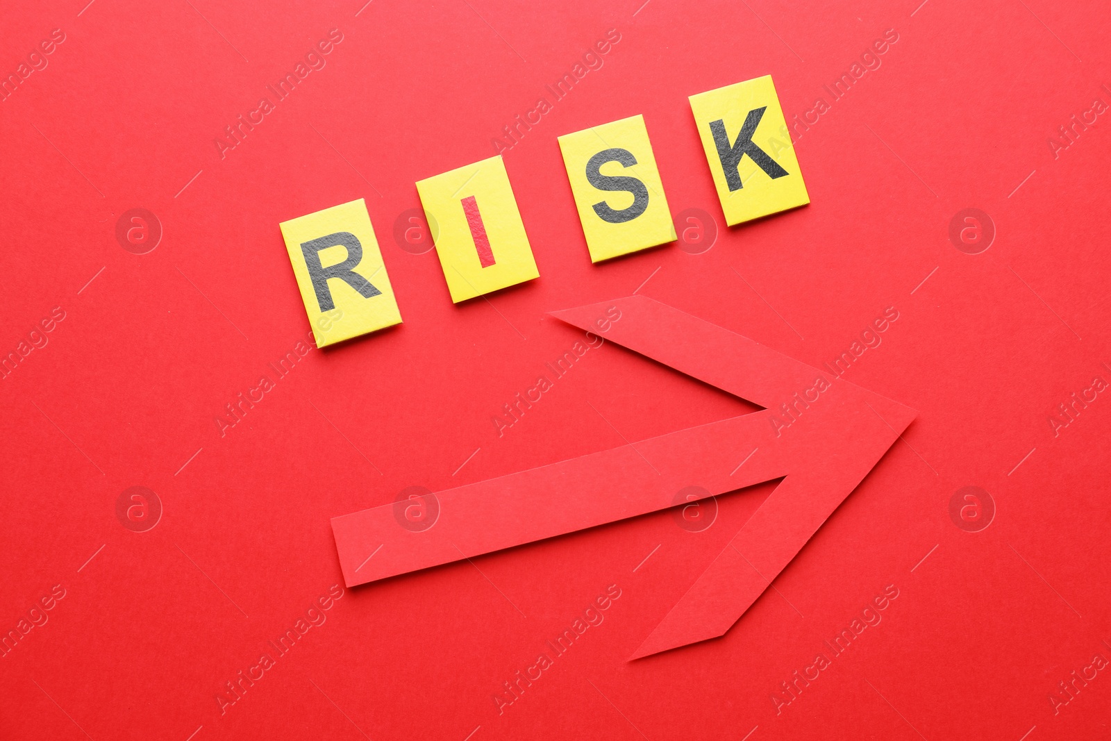 Photo of Word Risk and arrow on red background, flat lay