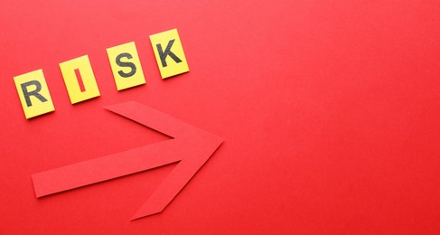 Photo of Word Risk and arrow on red background, flat lay. Space for text