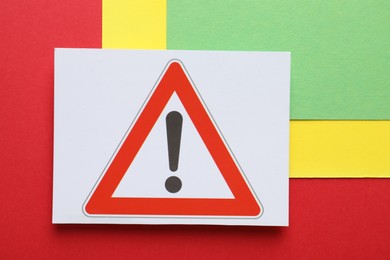 Photo of Risk. Sheet of paper with warning sign on color background, top view