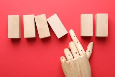 Photo of Mannequin hand throwing wooden block on red background, flat lay with space for text. Domino effect