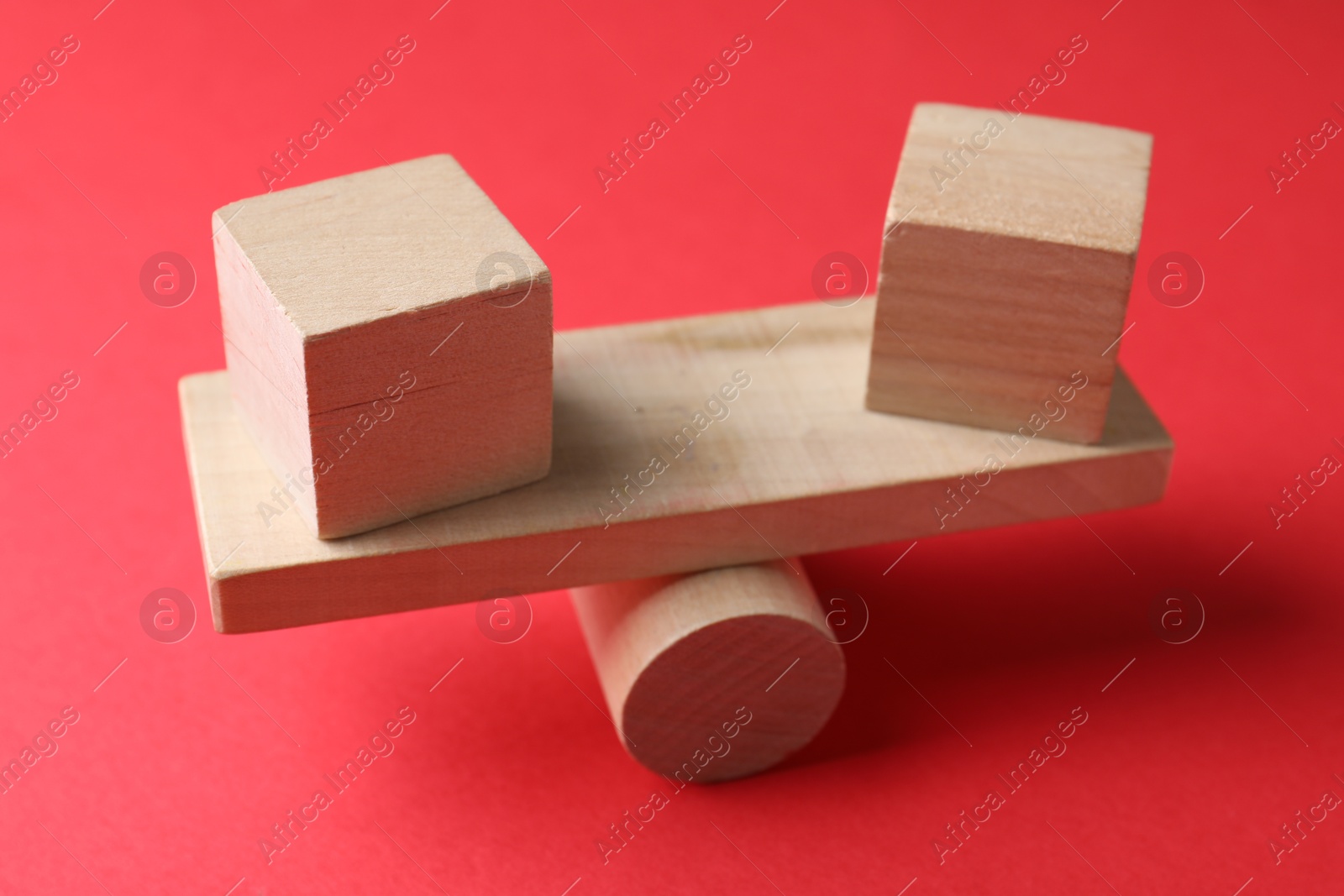Photo of Risk. Wooden seesaw scale with cubes on red background, closeup