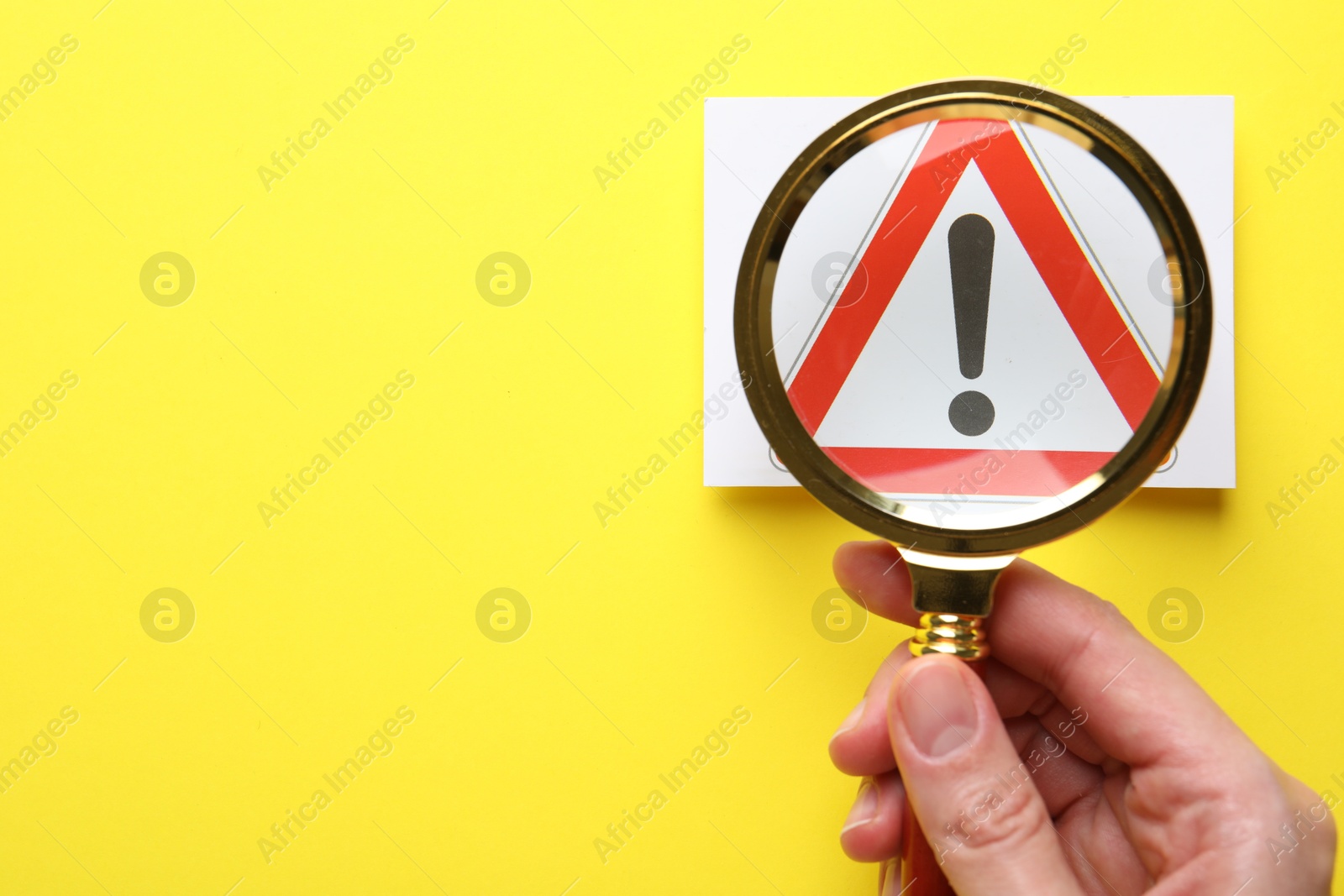 Risk. Woman with magnifying glass and warning sign on yellow background, top view. Space for text Photo of Risk. Woman with magnifying glass and warning sign on yellow background, top view. Space for text