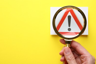 Photo of Risk. Woman with magnifying glass and warning sign on yellow background, top view. Space for text