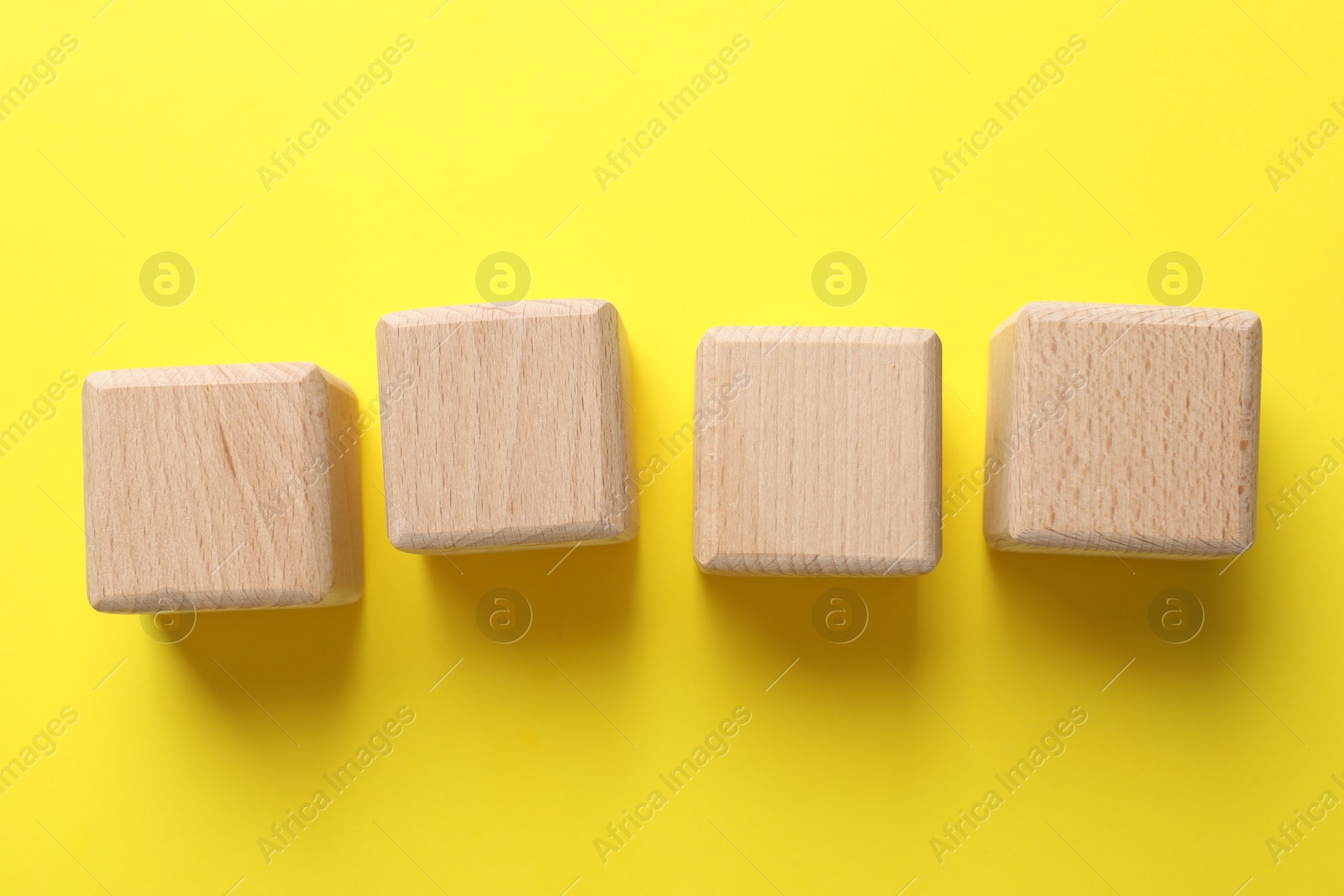 Photo of Blank wooden cubes on yellow background, flat lay