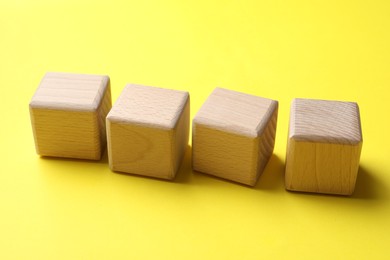 Photo of Blank wooden cubes on yellow background, closeup