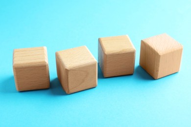 Photo of Blank wooden cubes on light blue background, closeup