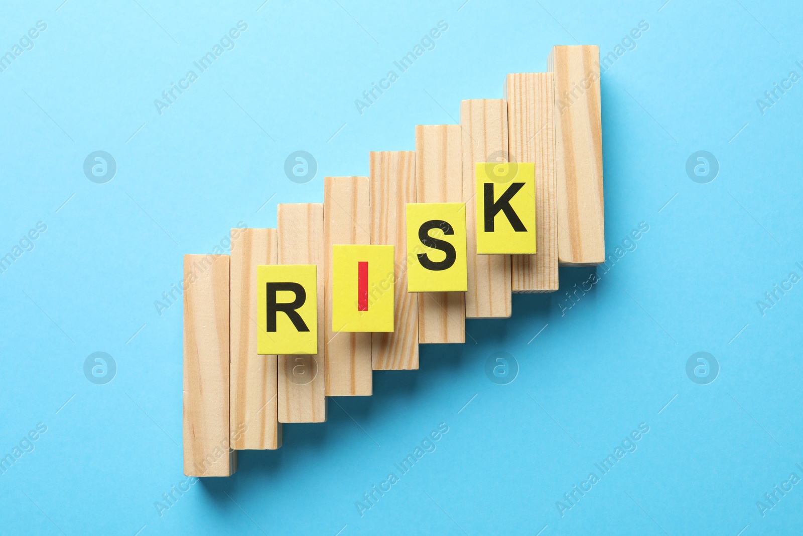 Photo of Word Risk and wooden blocks on light blue background, flat lay