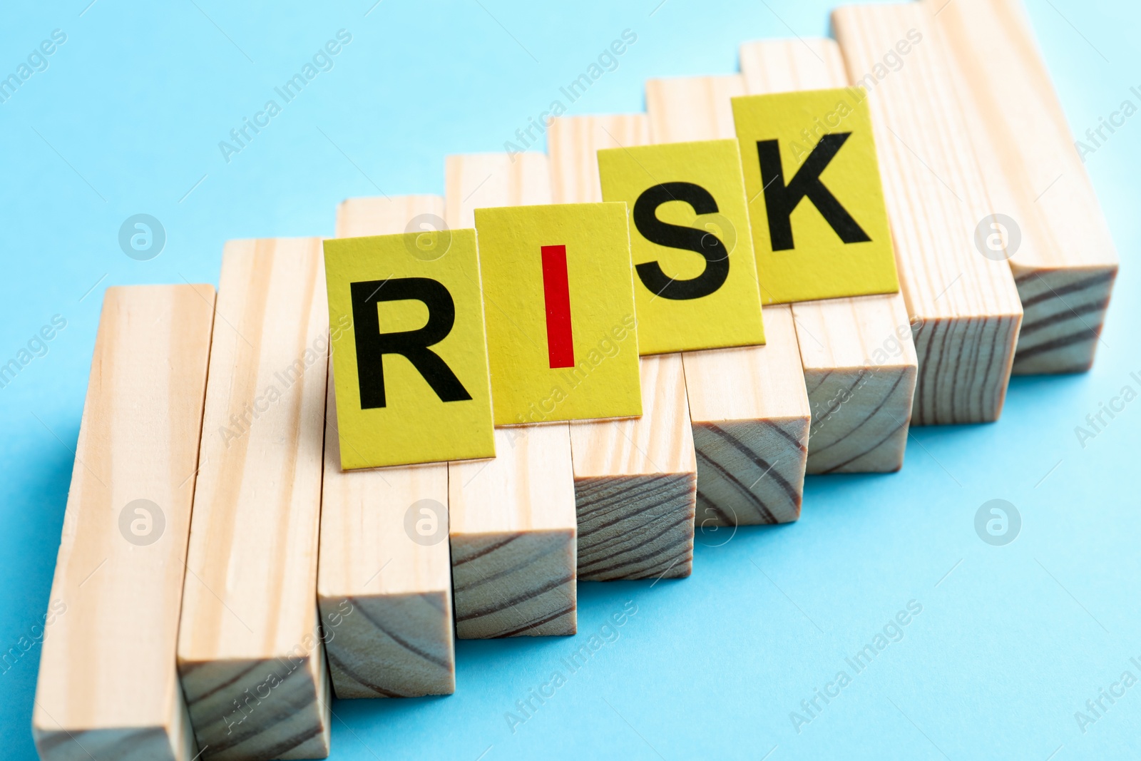 Photo of Word Risk and wooden blocks on light blue background, closeup