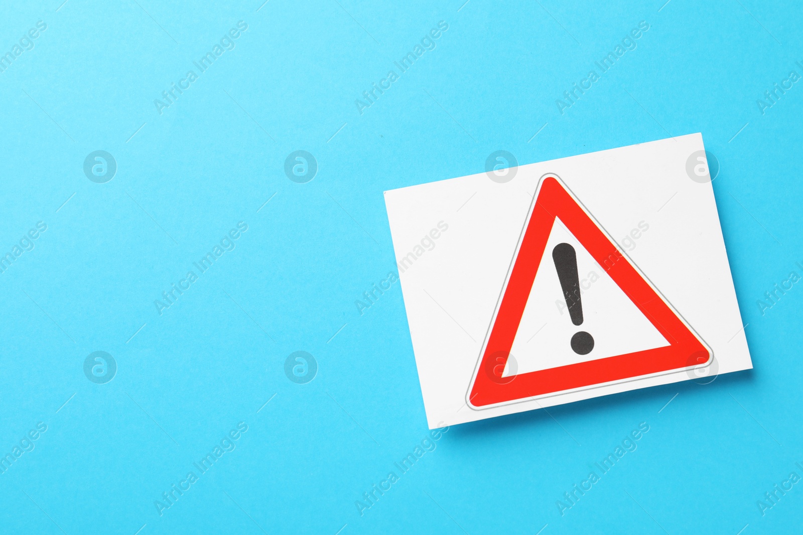 Photo of Risk. Sheet of paper with warning sign on light blue background, top view and space for text