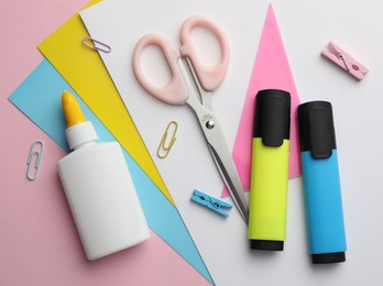 Photo of Glue in bottle, color paper and other stationery on pink background, flat lay