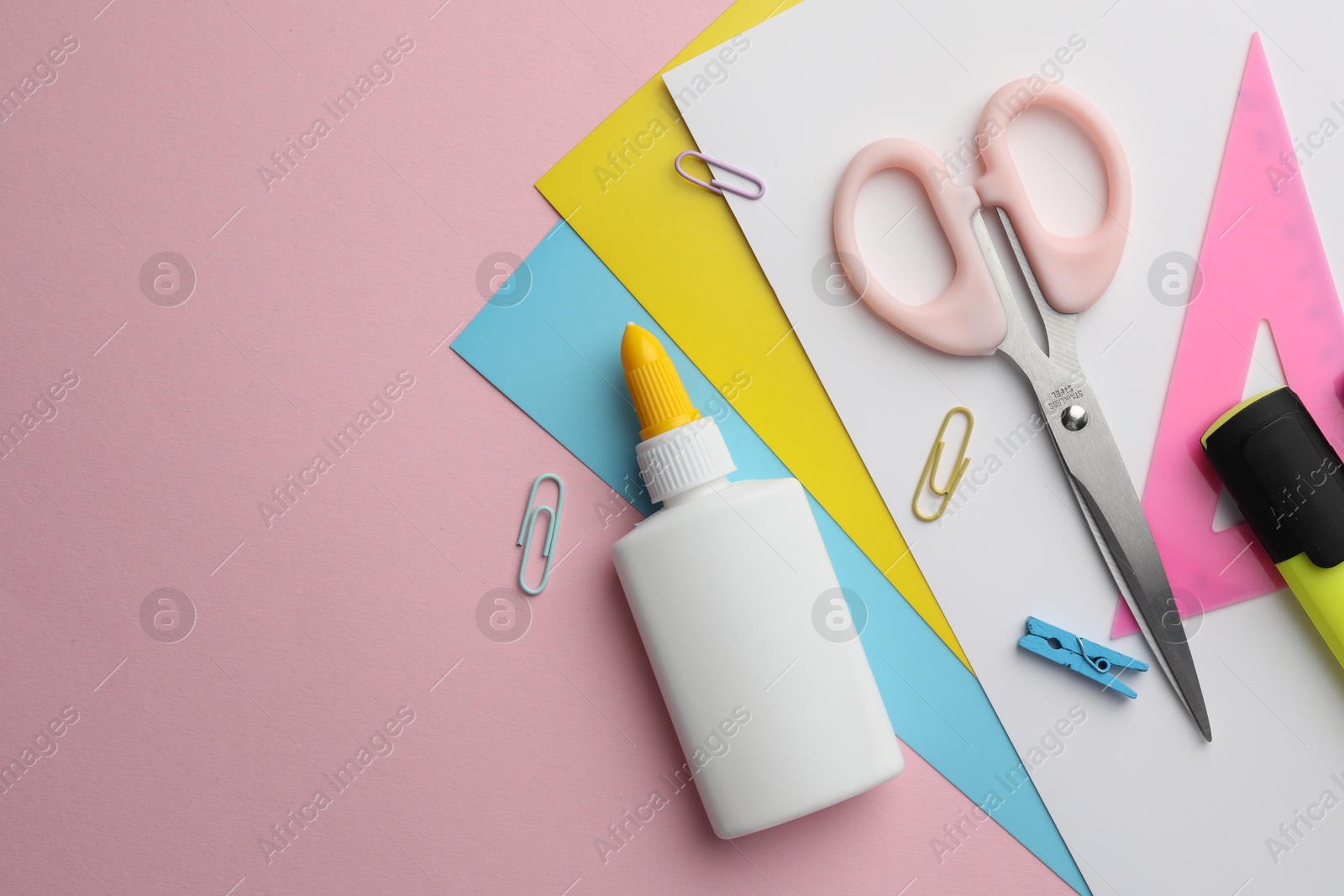 Photo of Glue in bottle, color paper and other stationery on pink background, flat lay. Space for text