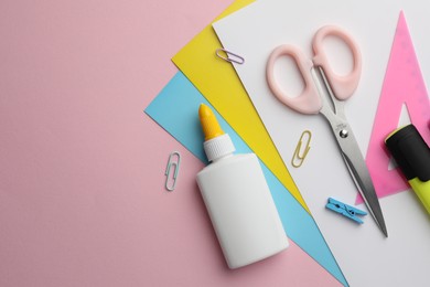 Photo of Glue in bottle, color paper and other stationery on pink background, flat lay. Space for text