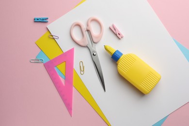 Photo of Glue in bottle, color paper and other stationery on pink background, flat lay