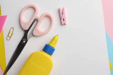 Photo of Glue in bottle, color paper and scissors on pink background, flat lay. Space for text
