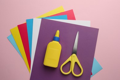 Photo of Glue in bottle, scissors and color paper on pink background, flat lay