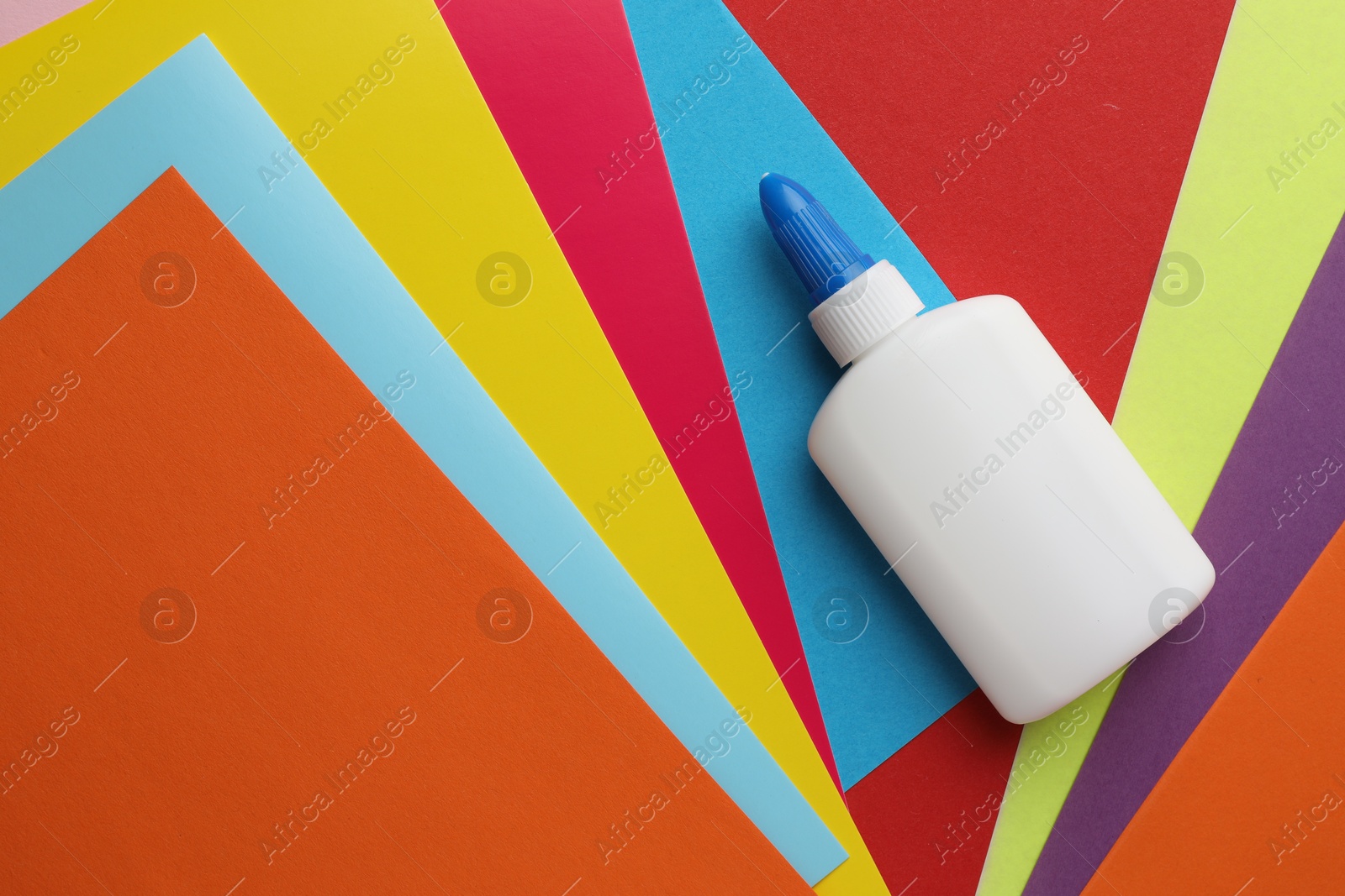 Photo of Glue in bottle on color paper, top view. Space for text