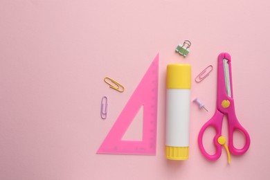 Photo of Glue stick, ruler, scissors and paper clips on pink background, flat lay. Space for text