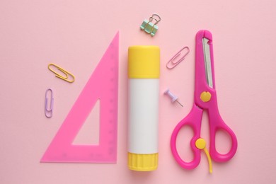 Photo of Glue stick, ruler, scissors and paper clips on pink background, flat lay