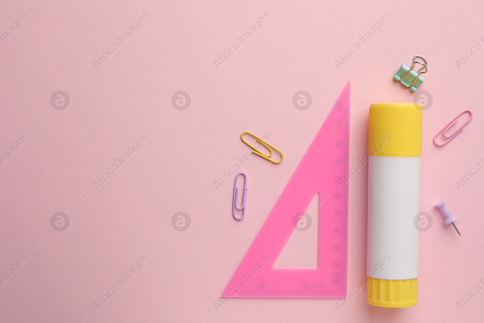Photo of Glue stick, ruler and paper clips on pink background, flat lay. Space for text