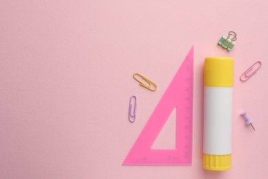 Photo of Glue stick, ruler and paper clips on pink background, flat lay. Space for text