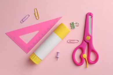 Photo of Glue stick, ruler, scissors and paper clips on pink background, flat lay