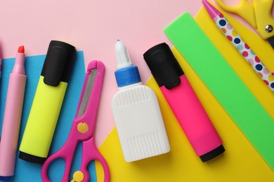 Photo of Glue in bottle, color paper and other stationery on pink background, flat lay