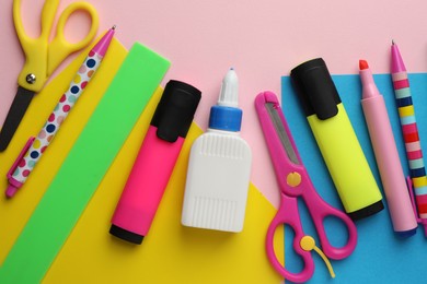 Photo of Glue in bottle, color paper and other stationery on pink background, flat lay