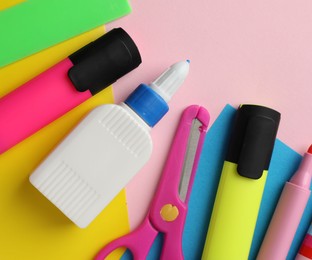 Photo of Glue in bottle, color paper and other stationery on pink background, flat lay