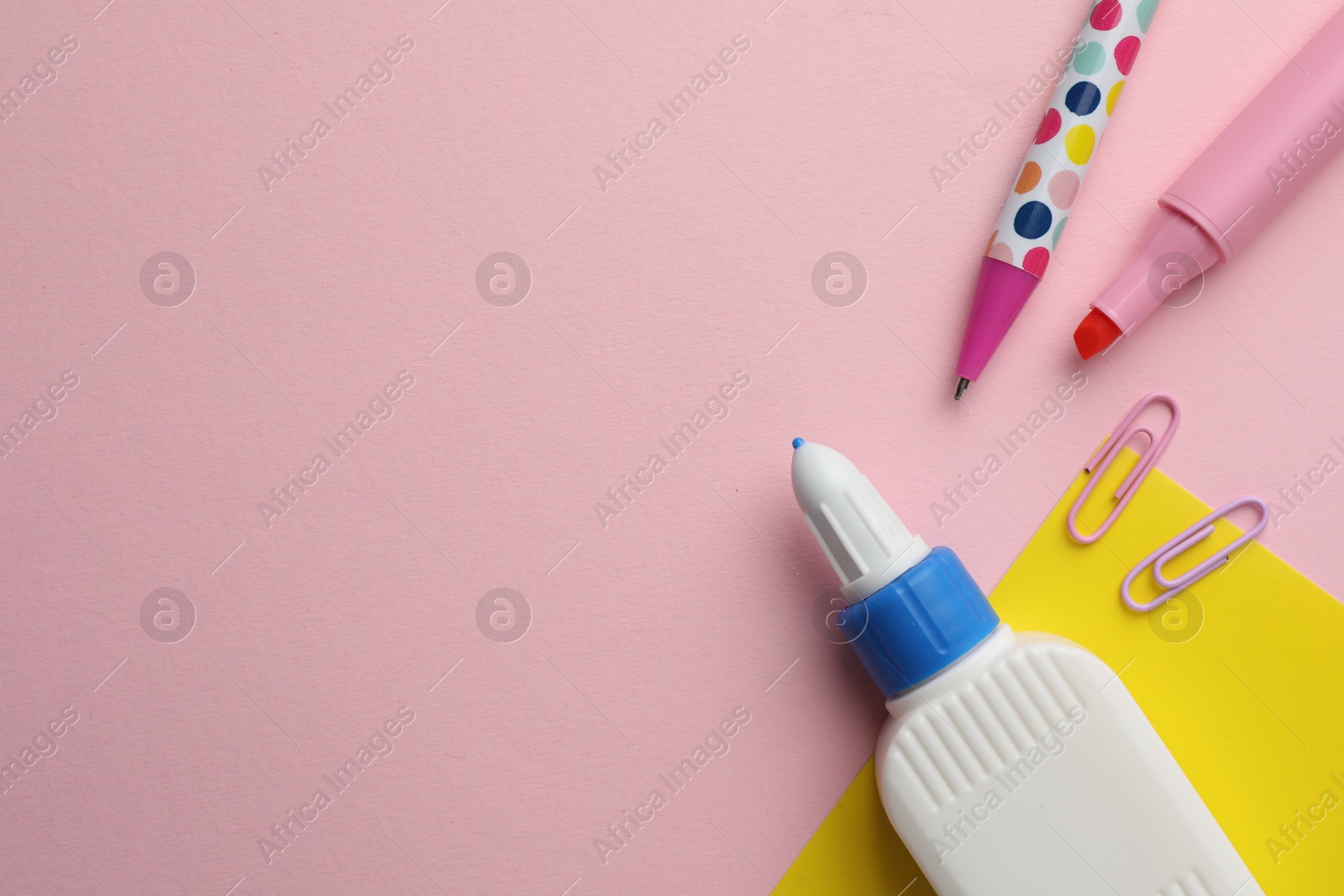 Photo of Glue in bottle, felt pen and paper clips on pink background, flat lay. Space for text