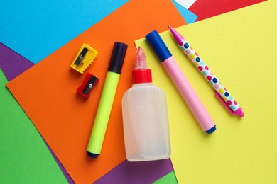 Photo of Glue in bottle and other stationery on color paper, flat lay