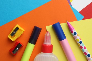 Photo of Glue in bottle and other stationery on color paper, flat lay