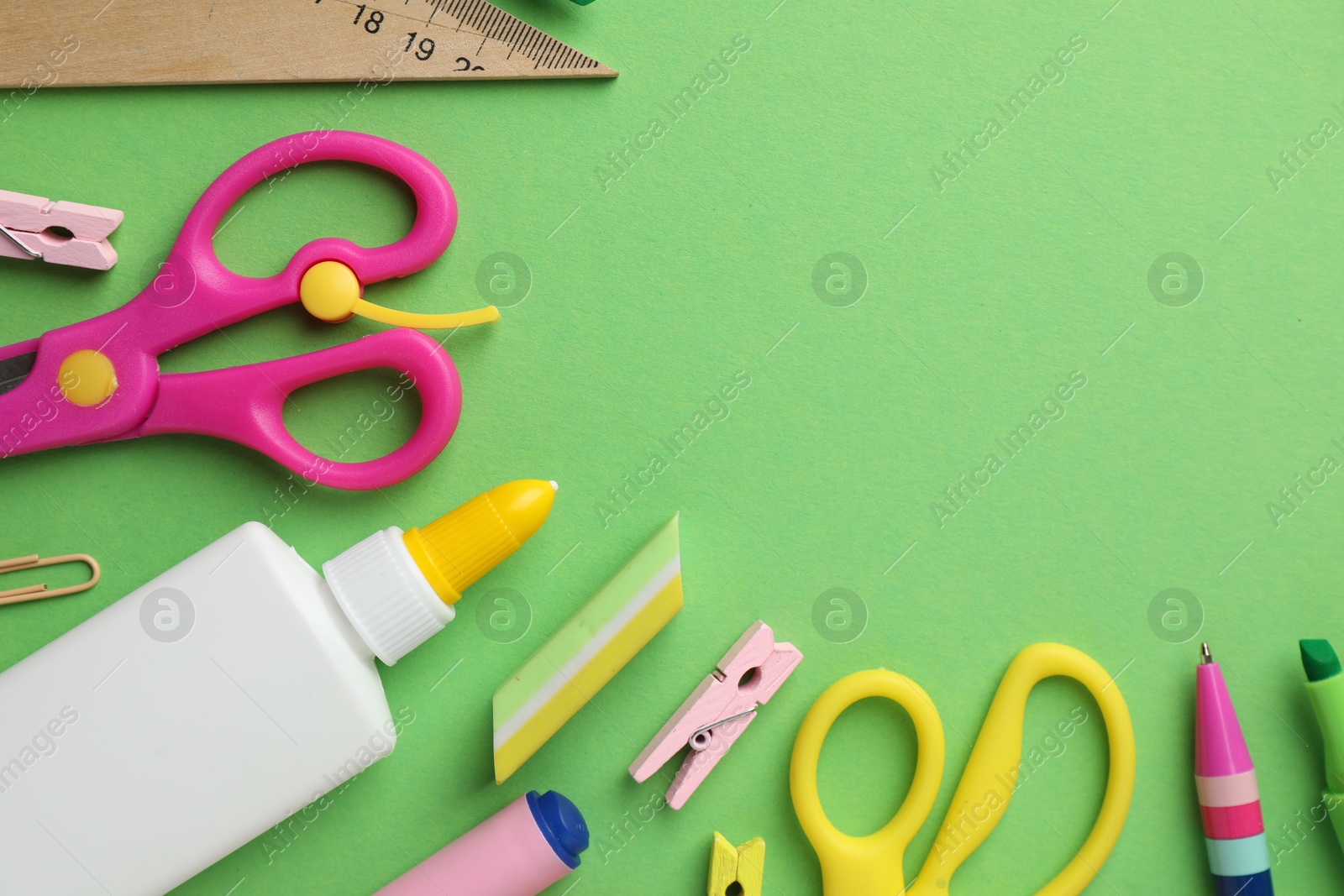 Photo of Glue in bottle and other stationery on green background, flat lay. Space for text