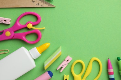 Photo of Glue in bottle and other stationery on green background, flat lay. Space for text